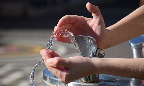childs-hands-cupping-water-from-water-fountain