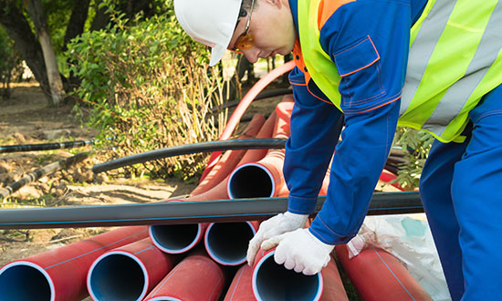 utility-worker-installing-red-pvc-pipe