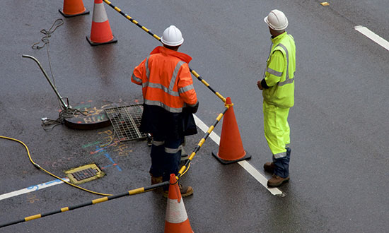 utility-workers-working-around-sewer-manhole-street